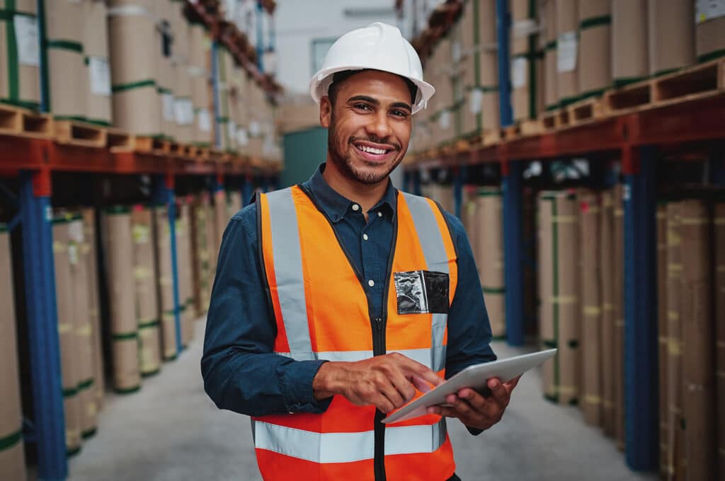 Cheerful young male manager using digital tablet in warehouse