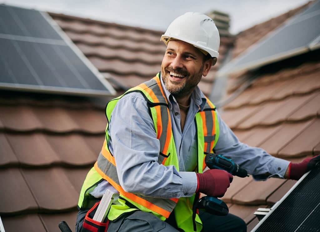 Happy technician securing solar panel to the mounting system on the roof.